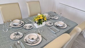 Una mesa de comedor con platos, vasos y cubiertos, rodeada de sillas.