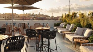 A rooftop terrace with outdoor seating, including tables and chairs, and a sofa area. - Hotel Bazaar - Fattal Colors (Tel Aviv)