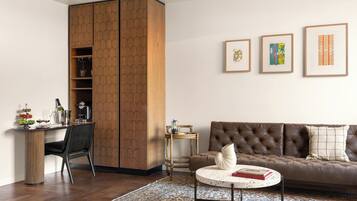 Una sala de estar moderna con un sofá de cuero marrón, una mesa de centro redonda, un aparador de madera y una mesita auxiliar.