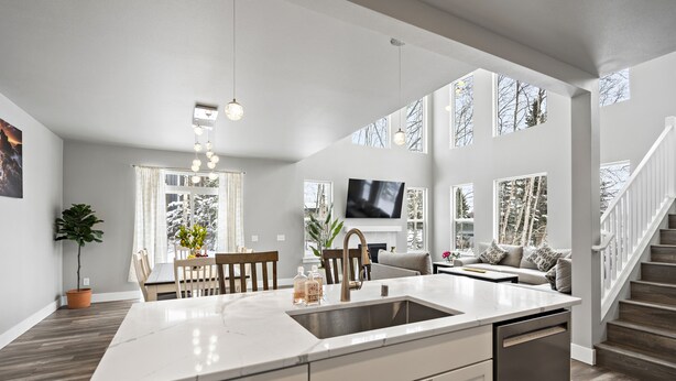 A spacious kitchen with a large island, a dining area with a table and chairs, a living room with a sofa and TV, and a staircase leading to another level. - LE'S SINGLE HOUSE WITH LAKE VIEW (Anchorage)