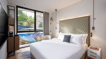 A modern hotel room with a large bed, a desk, a chair, a TV, and a view of a swimming pool.