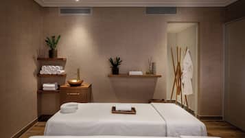 Un spa moderno con dos camas, un tocador de madera, un lavabo y un espejo grande.
