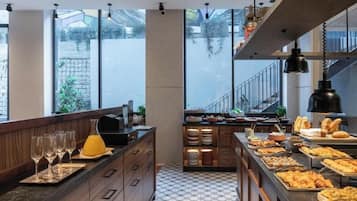 A modern kitchen with a long counter, various food items, and wine glasses.