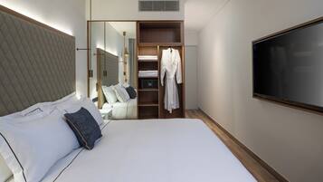 A hotel room with a large bed, a wardrobe, a television, and a mirror.