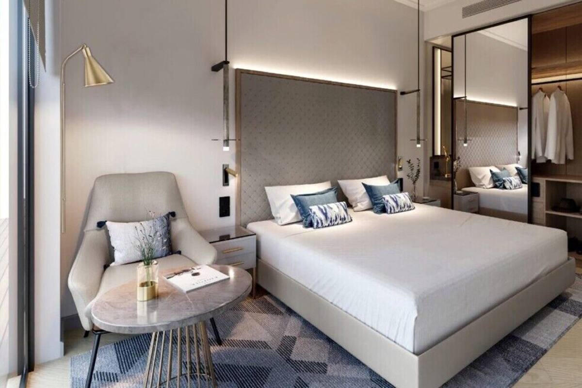 A modern bedroom with a large bed, bedside tables, a chair, a wardrobe, and a mirror.