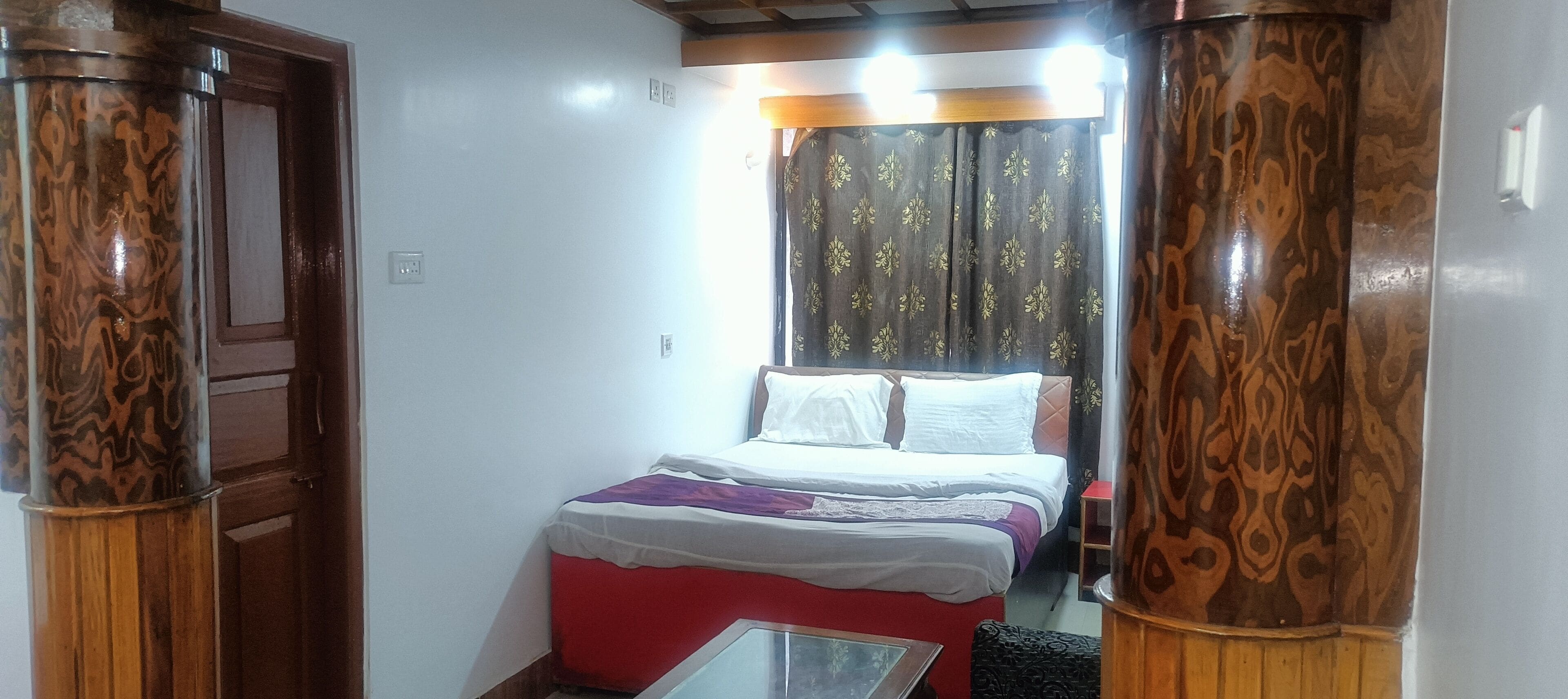 A bedroom with a bed, a nightstand, and a window with curtains.