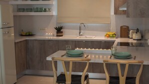 A modern kitchen with wooden cabinets, a central island with seating, and a variety of kitchenware. - Ostria, Pithos Apartments (Thira - Santorini)