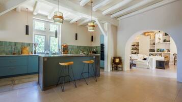 A modern kitchen with a central island, bar stools, and pendant lighting.