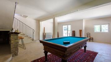 A spacious room with a pool table, a staircase, and a view of the outdoors.