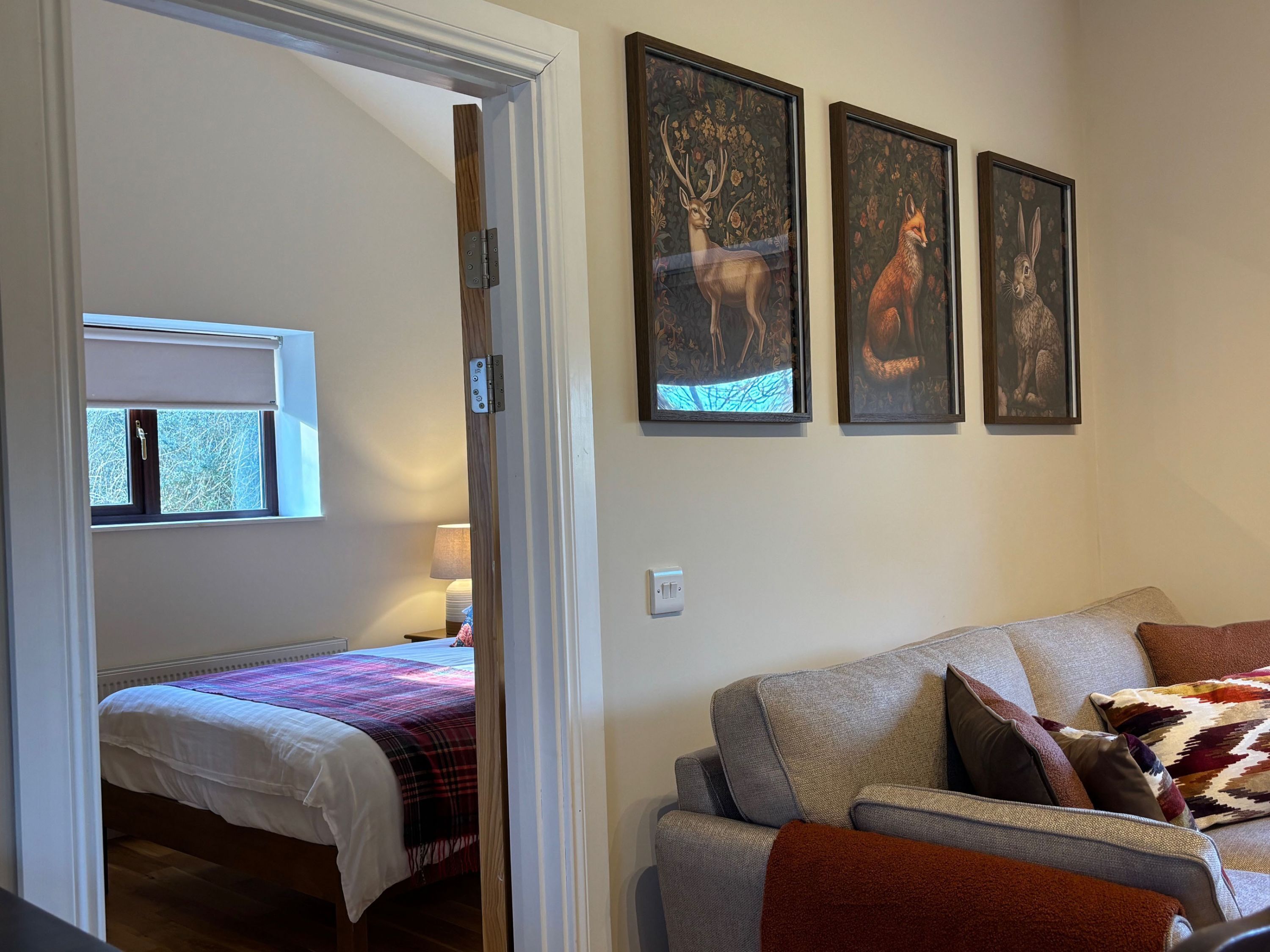 Een kamer met een bed, een slaapbank en drie ingelijste dierenportretten aan de wand.