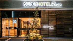 Das SuperHotel Premier mit modernem Design, mit einer markanten Eingangspforte und einer kleinen Grünfläche davor.