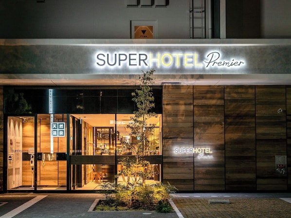 Exterior del SuperHotel Premier con un diseño moderno, que presenta una entrada destacada y un pequeño jardín delantero.
