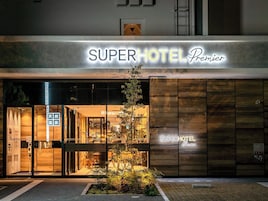 The exterior of the SuperHotel Premier with a modern design, featuring a prominent entrance and a small garden area in front.