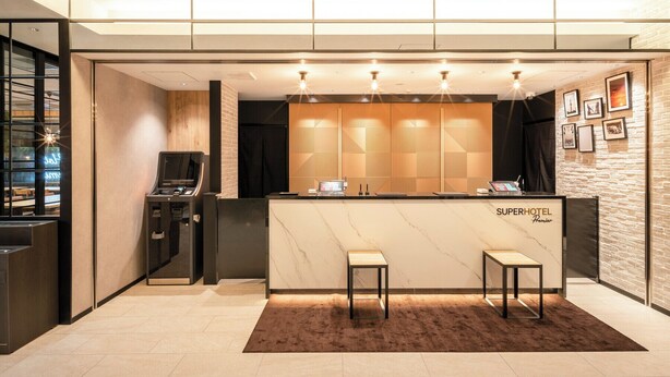 A hotel reception area with a marble counter, a digital kiosk, and two seating areas. - Premier Nagoya Natural Hot Spring Sakura-dori Exit (Nagoya)
