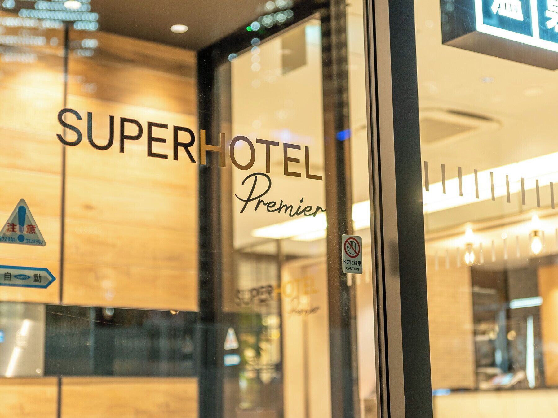 A hotel entrance with the name "SuperHotel Premier" visible on the glass door.
