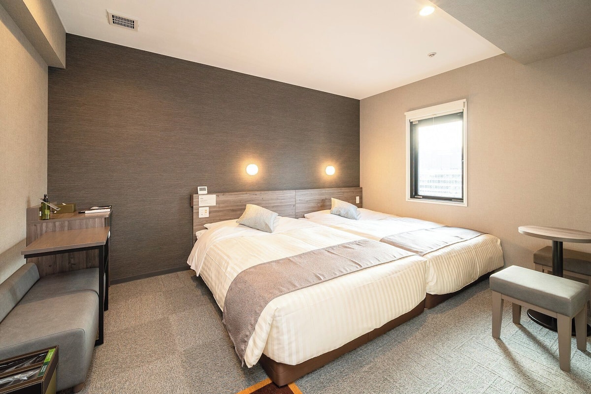 Une chambre d’hôtel moderne, dotée d’un grand lit, d’un bureau et d’une petite table.