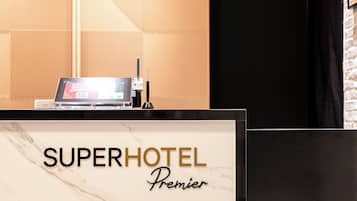 A reception desk with a digital screen, labeled "SUPERHOTEL Premier."