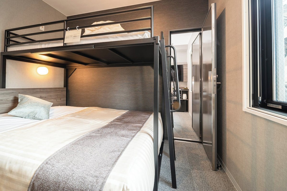 Une chambre avec un lit superposé, un réfrigérateur et une fenêtre.
