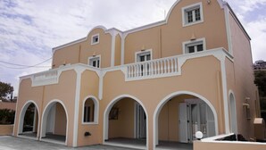 A two-story building with a curved facade, multiple arches, and a balcony with white balustrades. - Maistros, Pithos Apartments (Thira - Santorini)