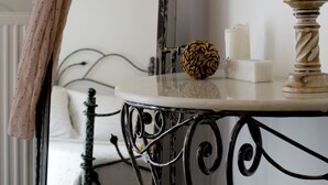 A bathroom with a mirror, a sink with candles, a decorative ball, and a chair. - Maistros, Pithos Apartments (Thira - Santorini)