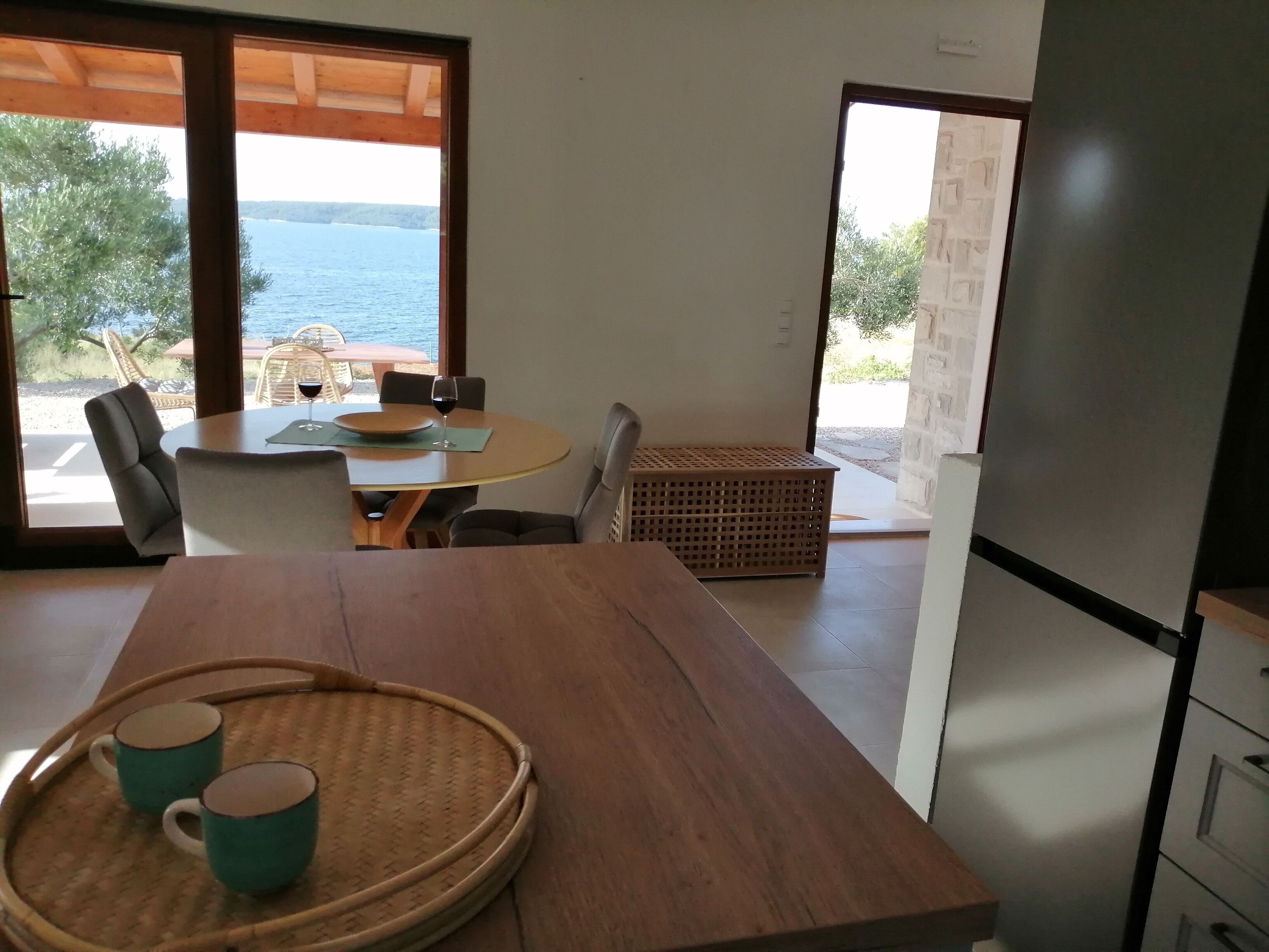A dining area with a wooden table, chairs, and a view of the sea.