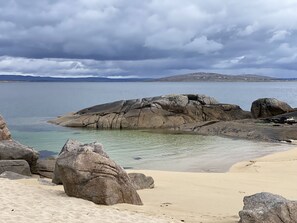A beach with large rocks and clear water.