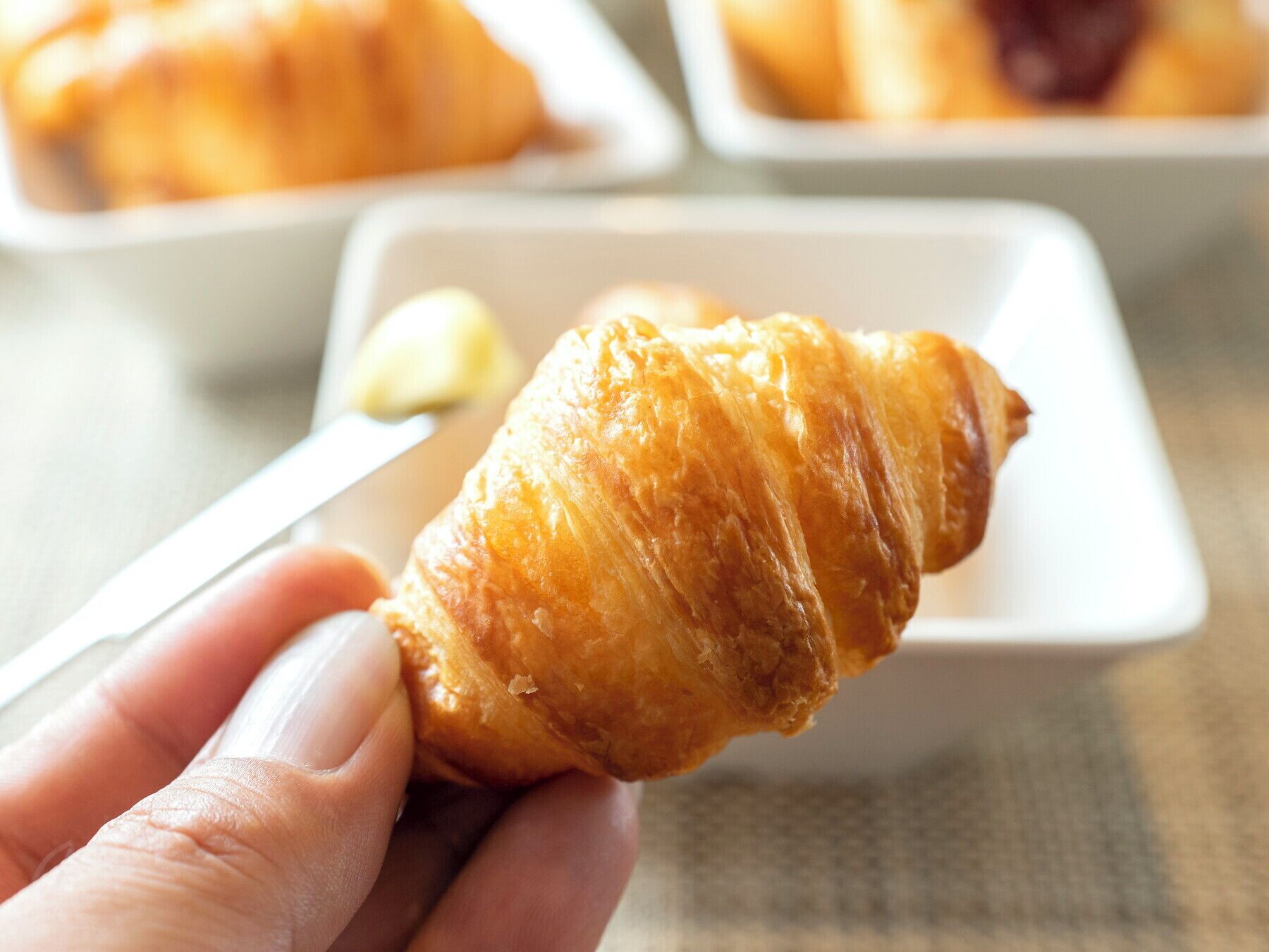 Una mano sosteniendo un croissant.