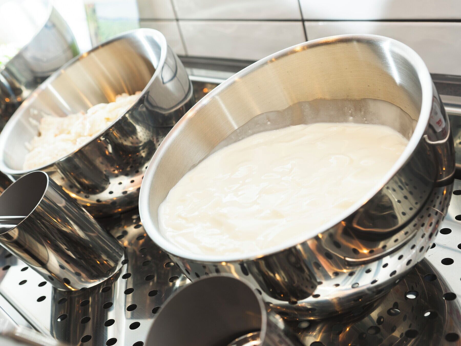 Stainless steel colander and bowls on a kitchen counter.