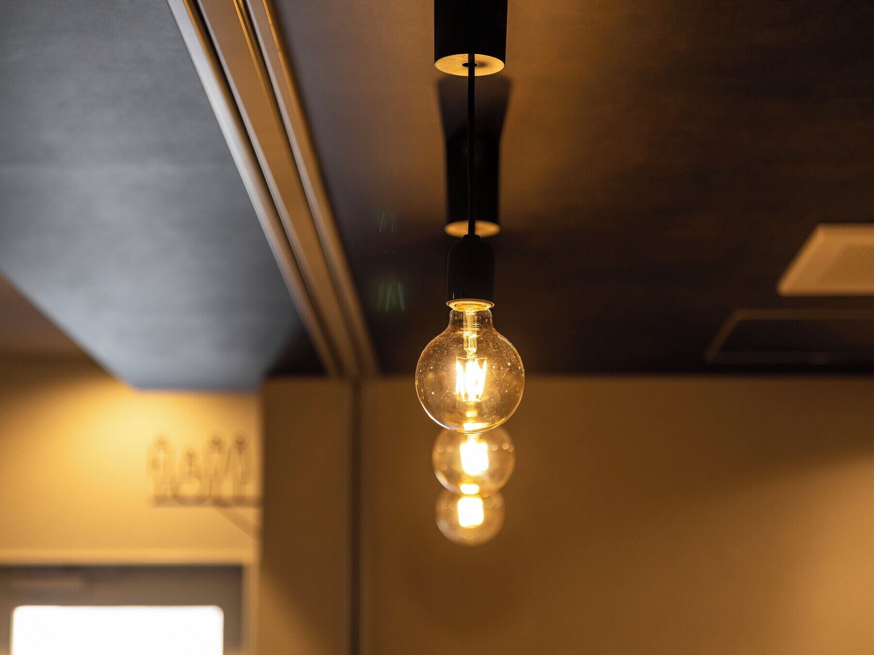 A pendant light with a clear glass bulb hanging from a black fixture.