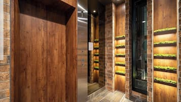 A modern elevator with wooden panels and green moss planters.