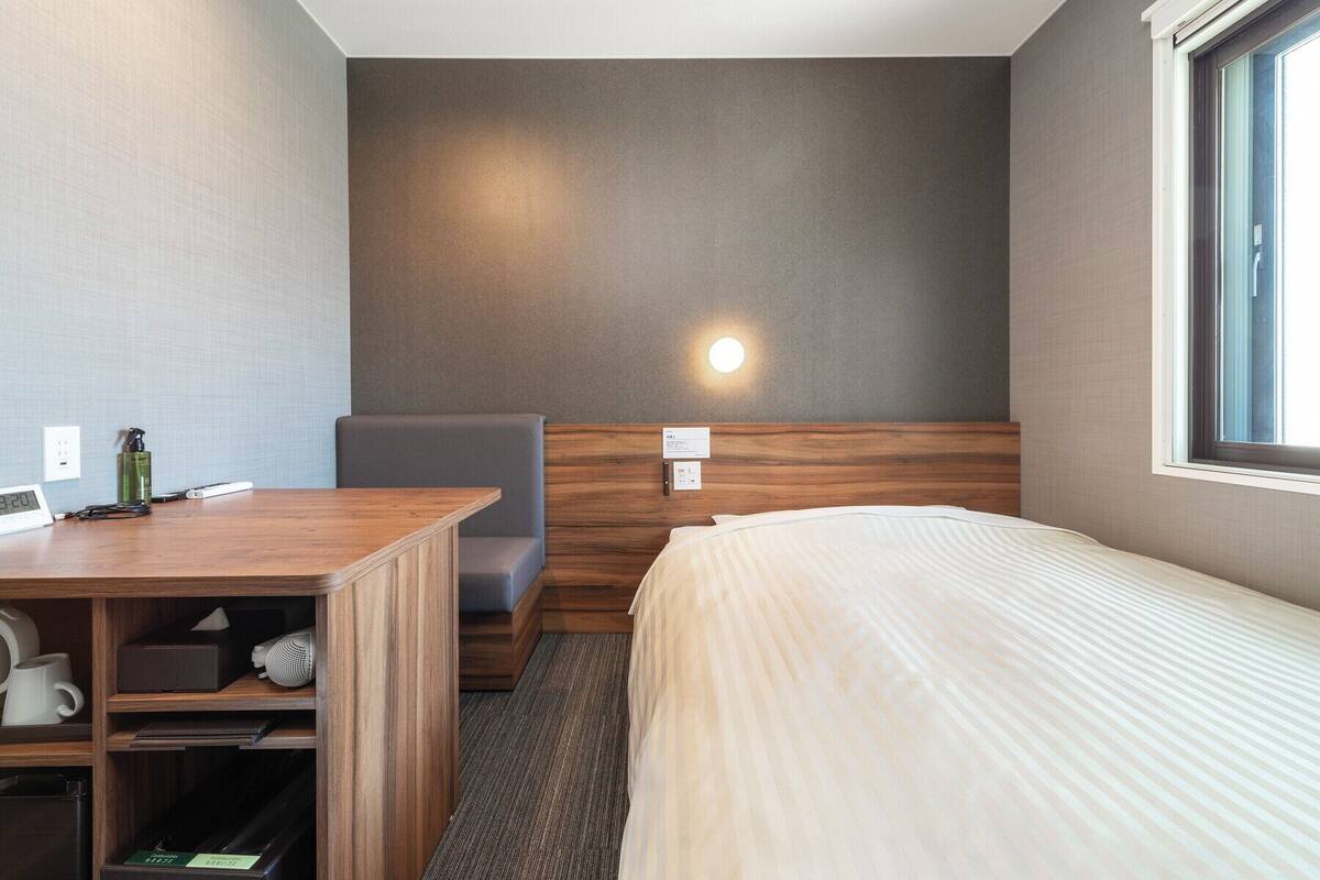 Una habitación de hotel con cama, escritorio, silla y una mesita.