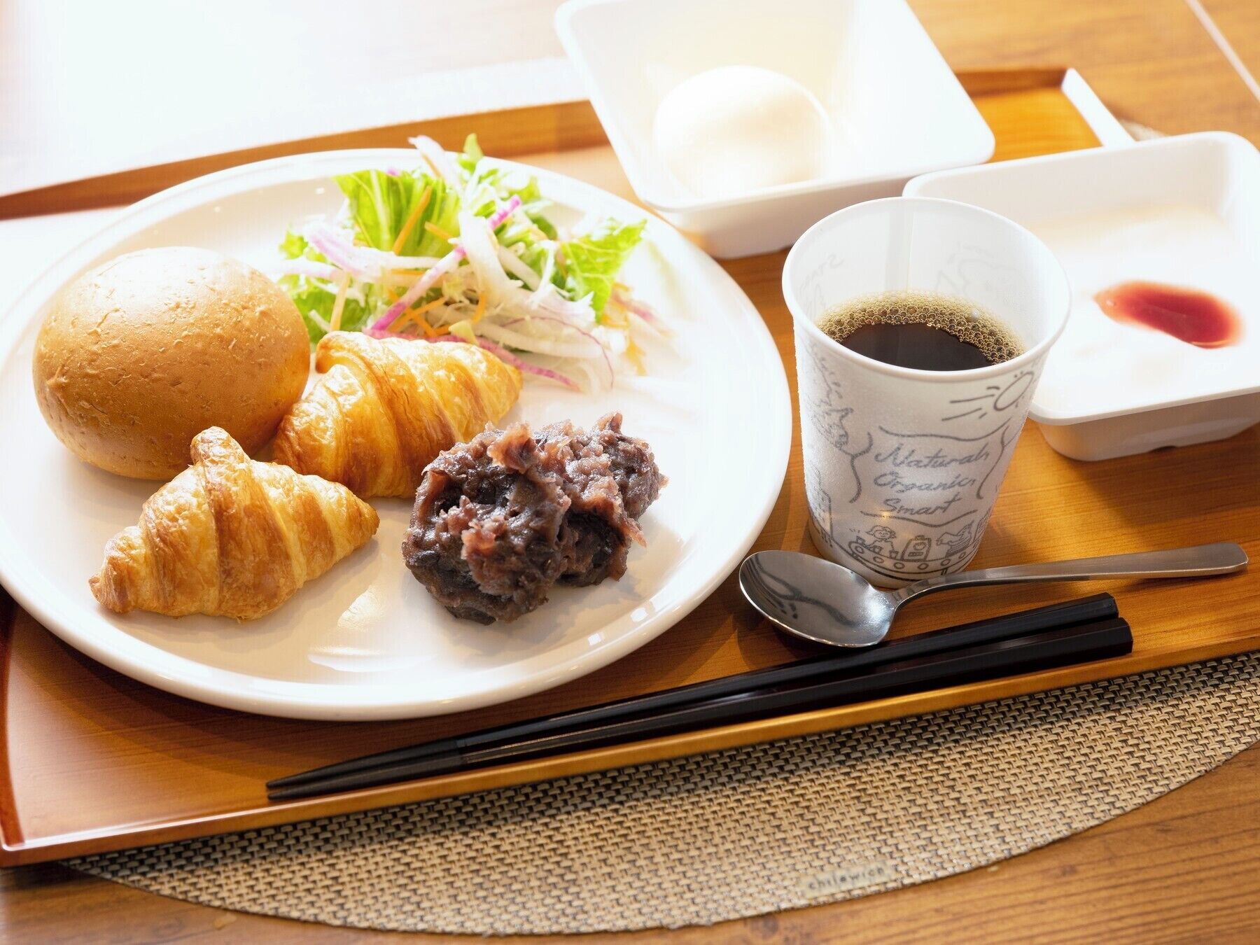 A plate with croissants, a salad, and a cup of coffee on a tray.