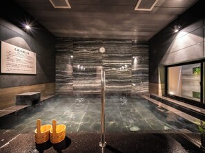 A modern spa room with a steam shower, a wooden bucket, and a wall-mounted clock. - SUPER HOTEL Nagoya Natural Hot Spring Shinkansenguchi (Nagoya)