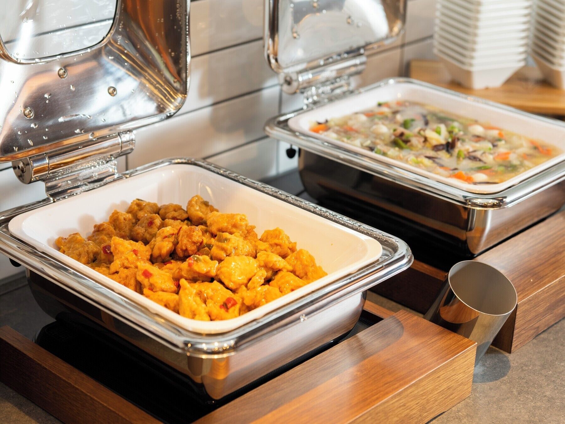 Servicio de comidas tipo buffet con bandejas de pollo y platos de verduras.