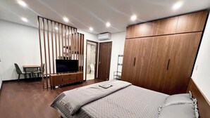 A bedroom with a large bed, a TV, a desk, and a wardrobe. - Hoàng Huy Riverside by HPT Home (Hai Phong)