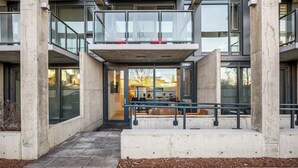A modern building with a central atrium, large windows, and a seating area with benches. - Modern Ground-Level Suite UG Parking, AC, C-Train (Calgary)