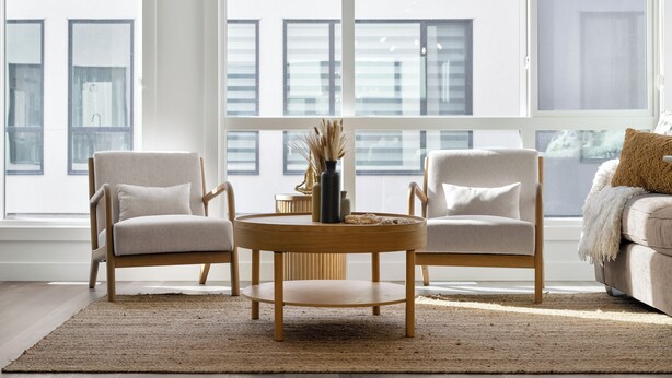 A modern living room with two armchairs, a round wooden coffee table, and a sofa with a throw blanket. - Western Chic Retreat 3BR w/ 3 Ensuites, Prkg, AC (Calgary)