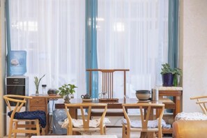 Una habitación con una mesa de comedor, sillas, un dispensador de agua y una planta en maceta.