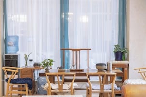 Una habitación con una mesa de comedor, sillas, un dispensador de agua y una planta en maceta.