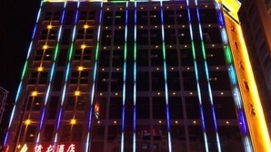 Ett hotell med en modern fasad, utmärkt av vertikala ljusband och en framträdande skylt högst upp.