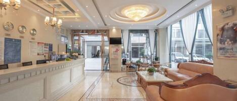 A hotel lobby with a reception desk, seating area, and large windows.