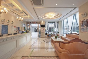 Vestíbulo de hotel con mostrador de recepción, zona de estar y ventanas amplias.