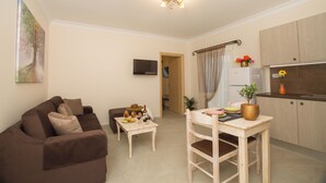 A living room with a brown sofa, a wooden coffee table, and a TV mounted on the wall.