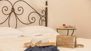 A neatly made bed with white linens, a bedside table with a book and glasses, and a decorative headboard.