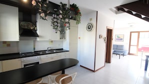 A kitchen with white cabinets, a black countertop, and a dining area with wicker chairs.