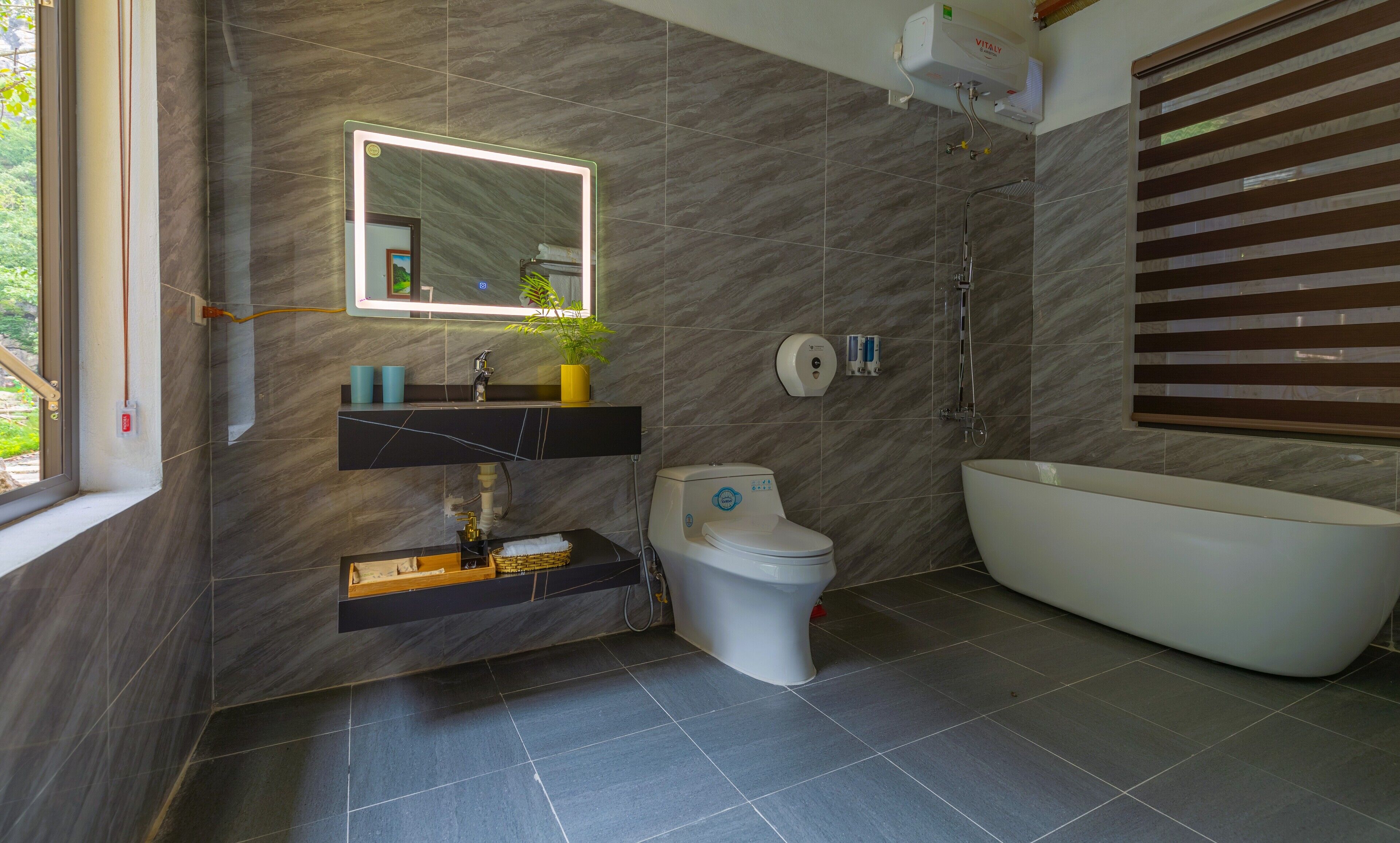 A modern bathroom with a marble wall, a built-in sink, a toilet, a shower, and a bathtub.