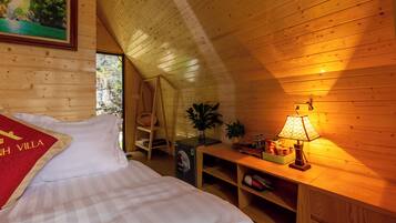 A cozy room with a bed, a desk with a lamp, a shelf with items, and a painting on the wall.