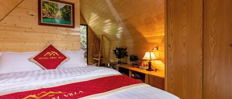 A wooden room with a bed, a nightstand, a lamp, and a framed picture on the wall.