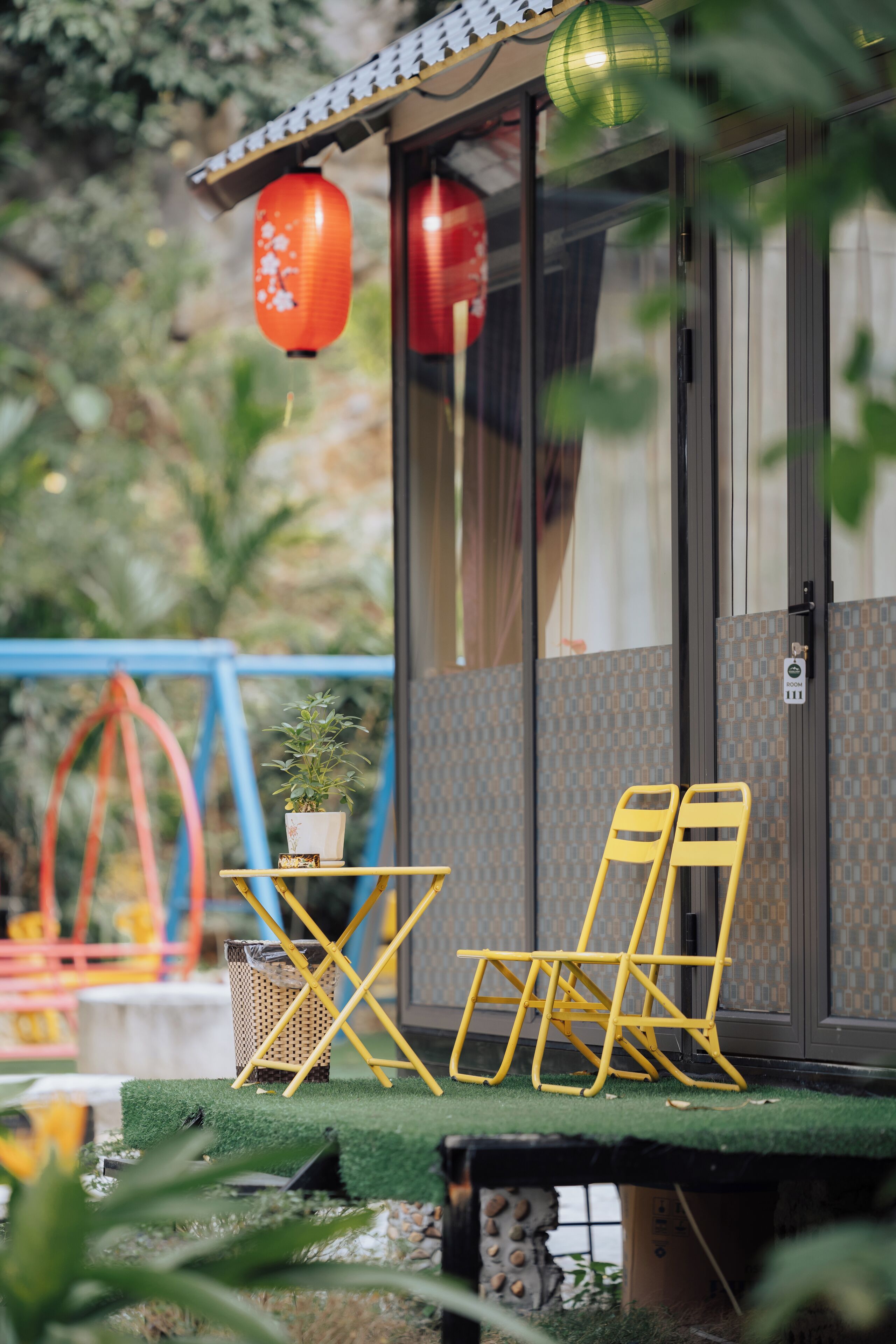 Une pièce dotée d’une porte coulissante, d’une petite table sur laquelle est posée une plante en pot, et de deux chaises jaunes.