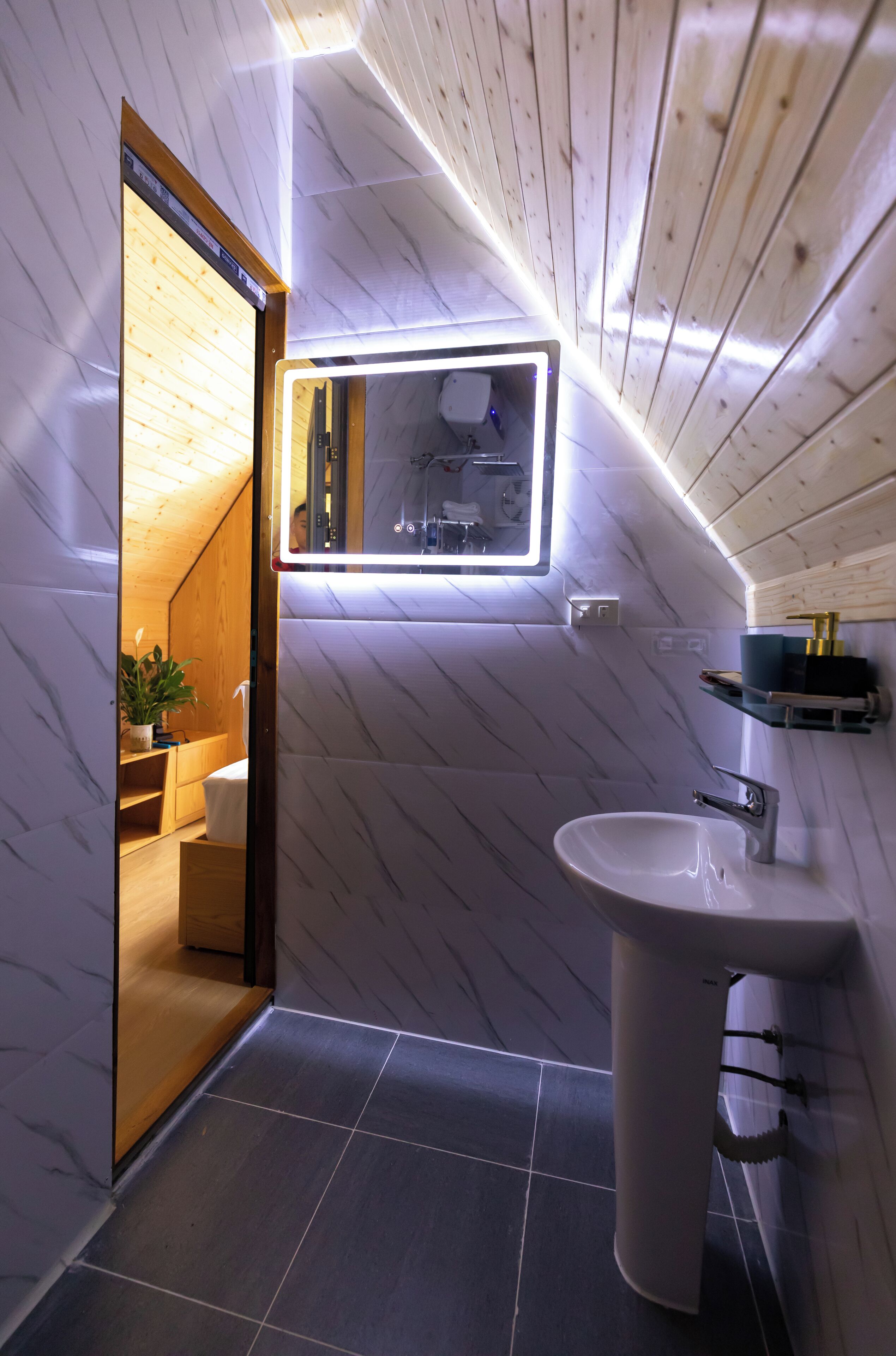 A modern bathroom with a wooden ceiling, a built-in sink, and a mirror with integrated lighting.